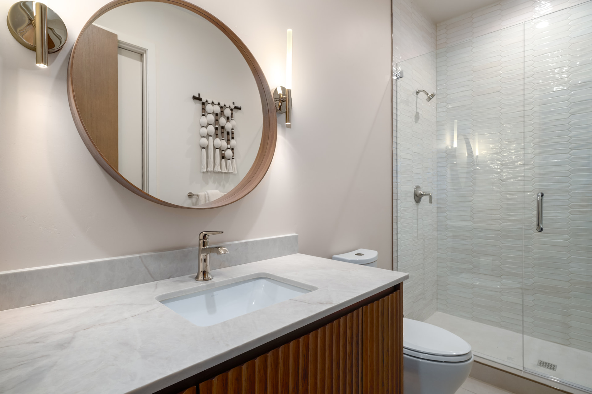 Guest bath with marble vanity, fluted walnut cabinetry and glass shower