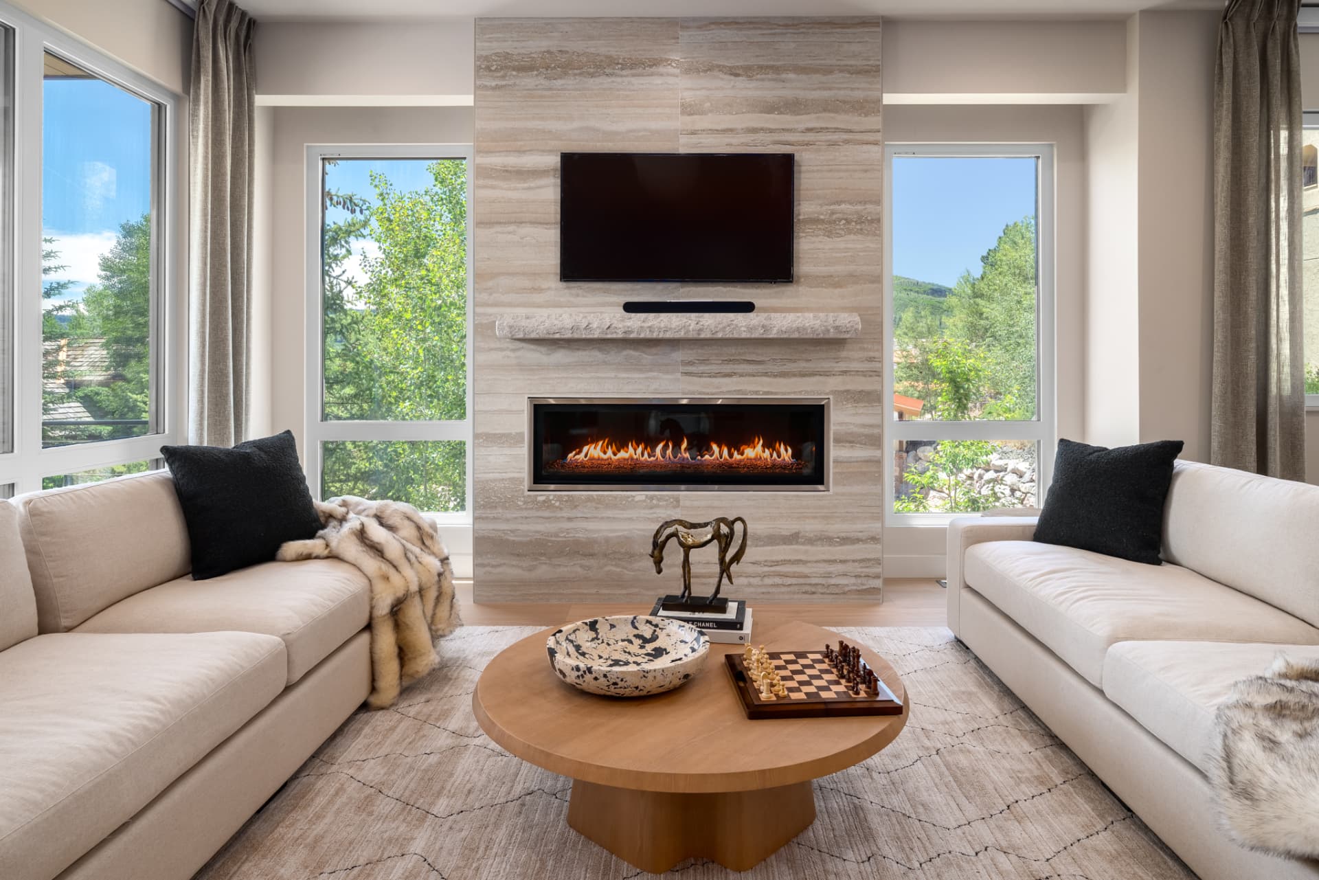 Living room with travertine fireplace surround, facing sofas and mountain views