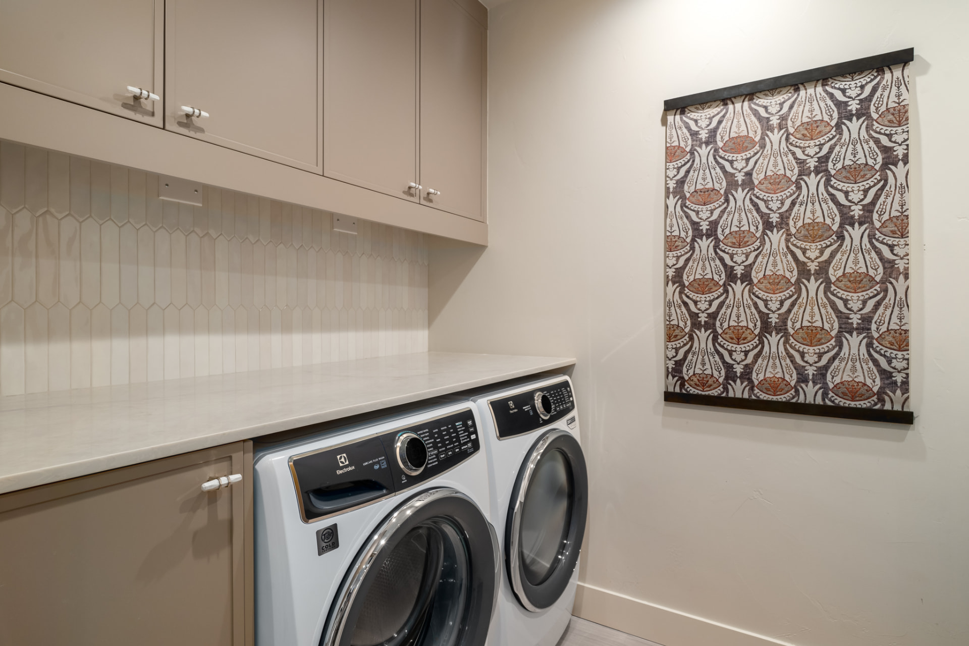 Full-size laundry room with side-by-side washer and dryer and custom cabinetry