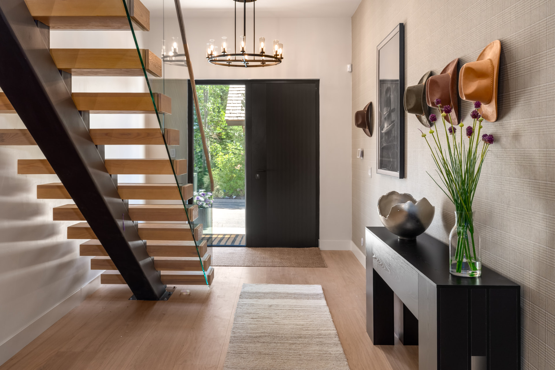 Entry foyer with floating white oak staircase, glass railing and iron chandelier