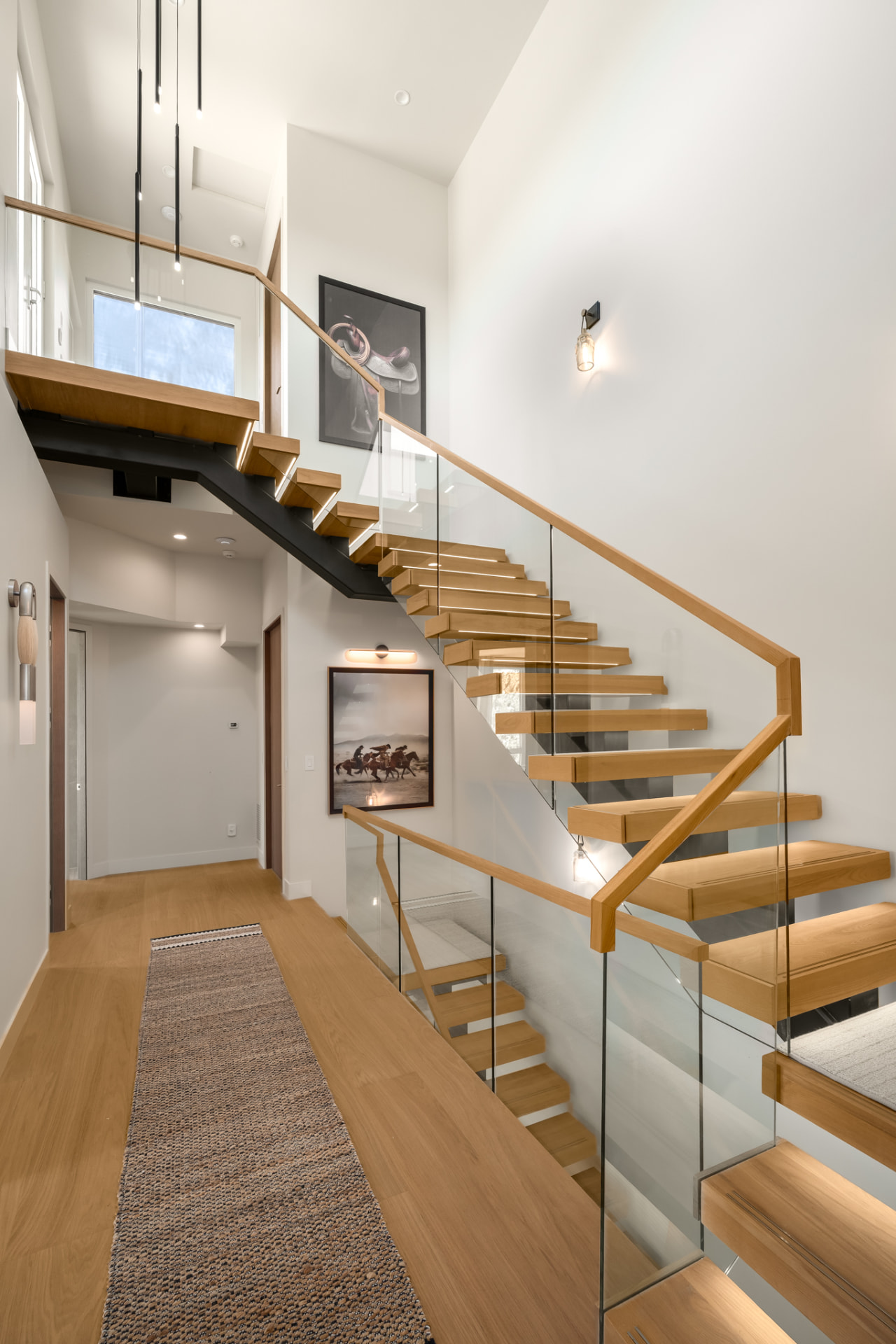 Floating white oak staircase with glass railing, gallery wall and open upper landing