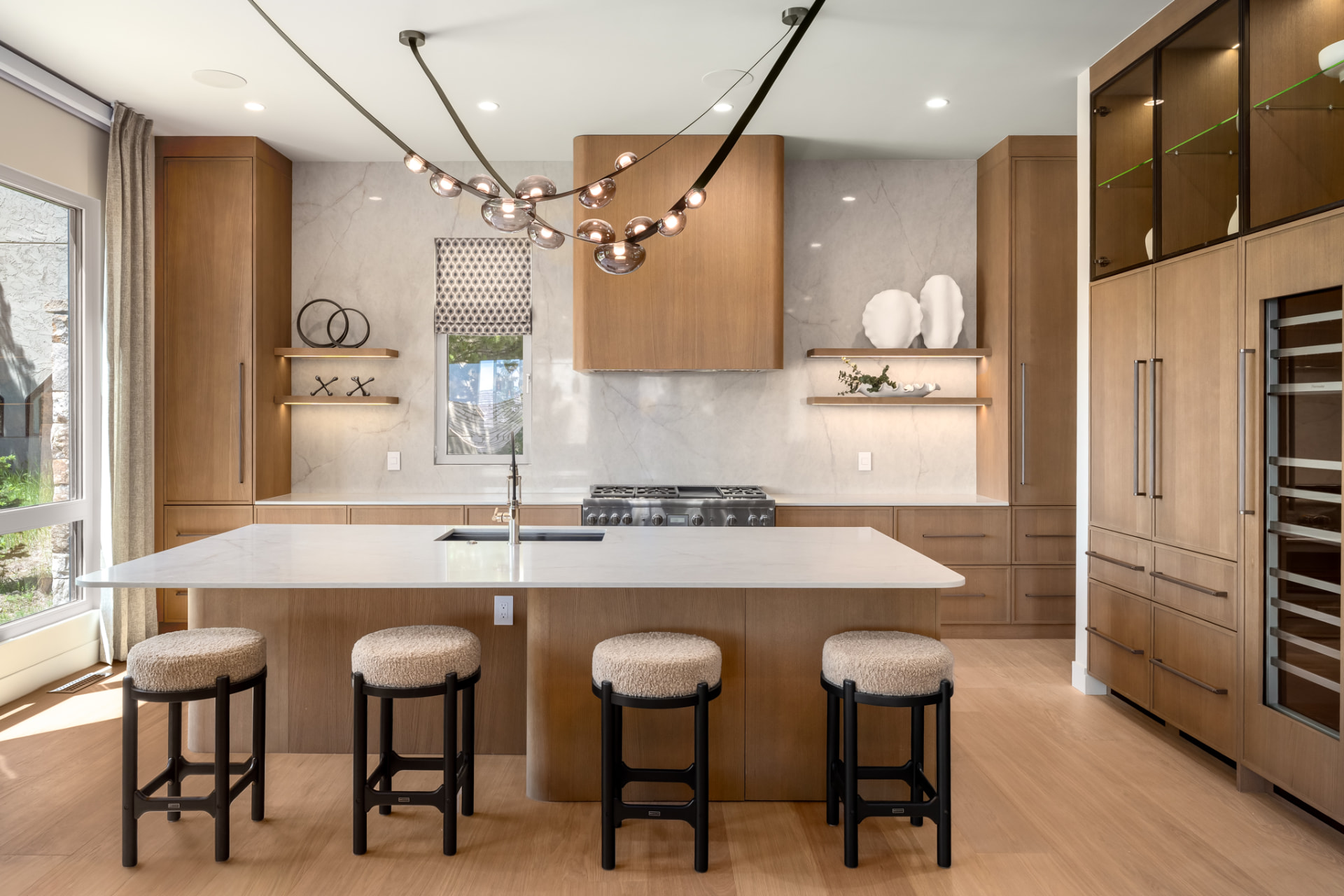 Chef's kitchen with sculptural chandelier, marble slab backsplash and island seating for four