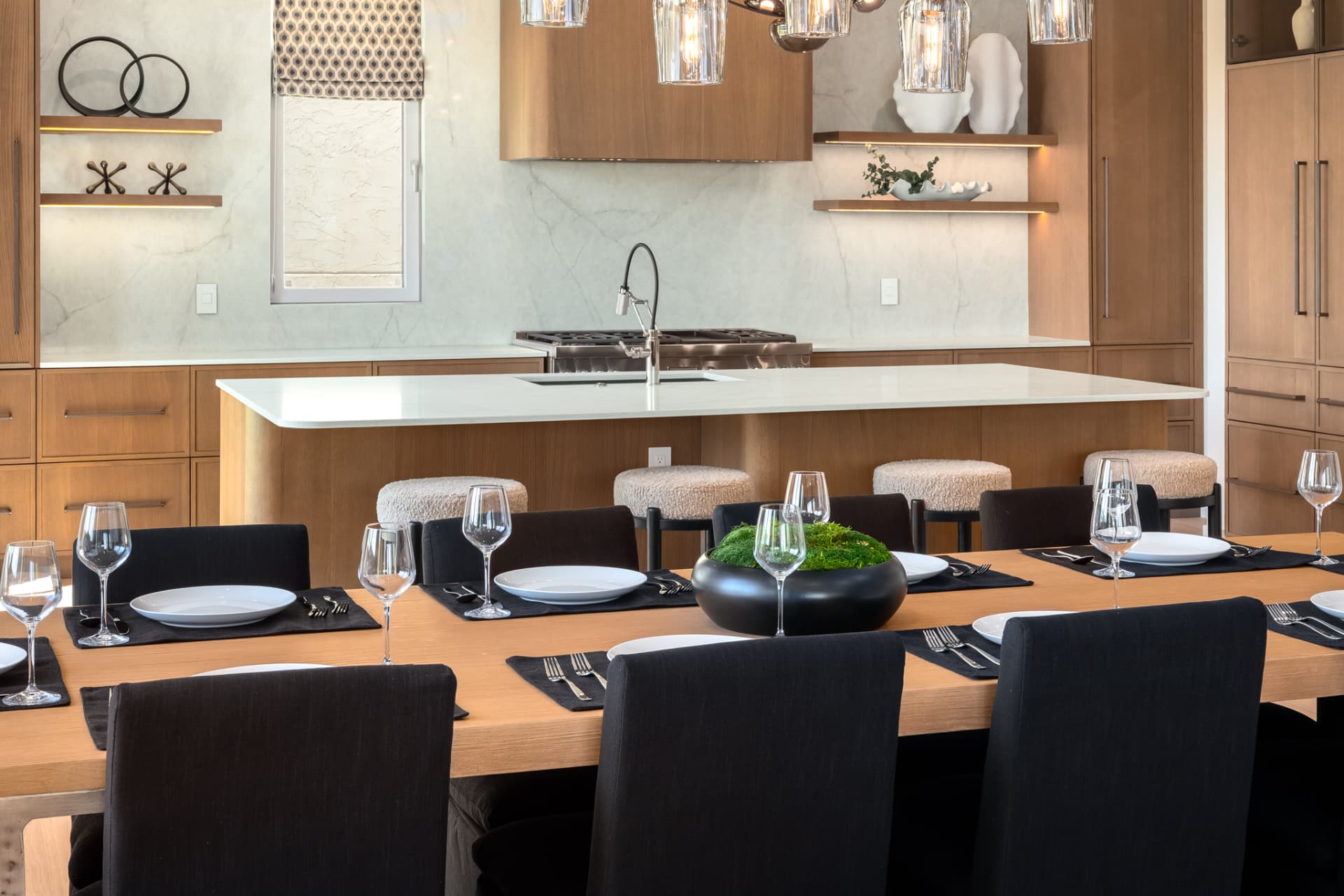 Dining table set with wine glasses looking toward the kitchen island